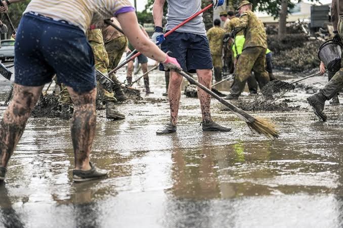 Emergency flood cleanup crew clearing silt, mud, and waterlogged insulation